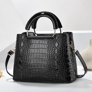Close-up of black crocodile embossed patent leather handbag with gold metal rings