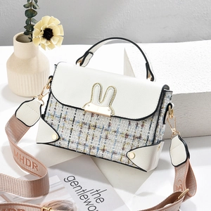Close-up of white PU leather and blue tweed crossbody bag with metal rabbit ear buckle