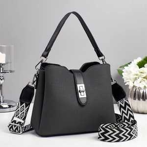Textured grey bucket bag with a patterned wide shoulder strap and silver clasp