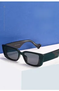 Macro view of dark green rectangular rimless sunglasses with wide temples on a display stand