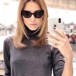 Detail shot of black cat-eye sunglasses with thick frames and dark lenses on a model