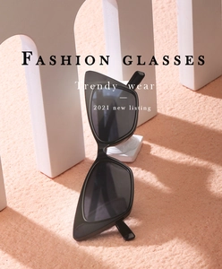 Detail of black cat-eye sunglasses on stone pedestal with soft pink background