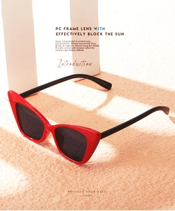 Detail of red cat-eye sunglasses with UV protection lenses on a sandy summer background