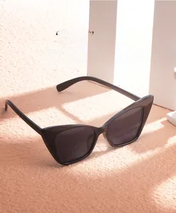 Detail of trendy black cat-eye sunglasses with sleek frames on minimalist orange background