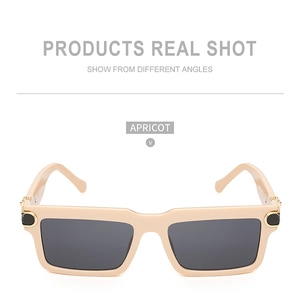 Detailed front view of apricot square sunglasses with grey lenses and gold metal accents