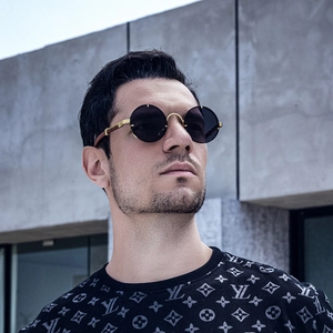 Detail of retro round sunglasses with gold metal bridge on a model wearing a monogram shirt