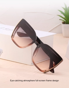 Cat-eye sunglasses with brown gradient lenses and gold metal trim on a white prop
