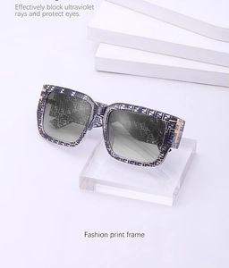 Detail of square oversized sunglasses featuring a logo pattern frame and metallic hinges