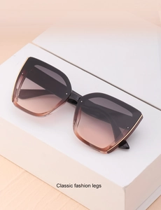 Detail of oversized cat eye sunglasses with gradient lenses and gold metal trim on frame