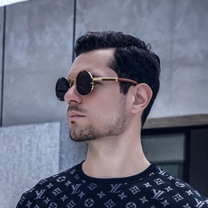 Detail view of round vintage sunglasses with gold frame and leopard metal logo