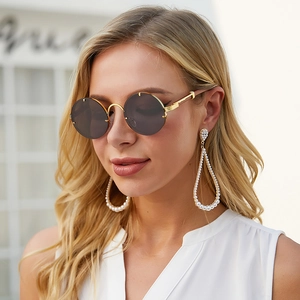 Detailed close-up of retro round gold sunglasses and ornate oversized pearl earrings