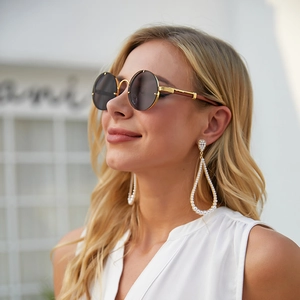 Detail of vintage round sunglasses with gold frames and large hollow pearl drop earrings