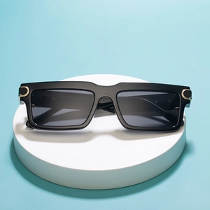 Fashionable black square sunglasses with gold C-shaped metal hinges on a blue background