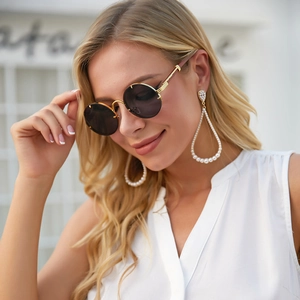 Detail of vintage round sunglasses with gold frames and elegant pearl drop earrings