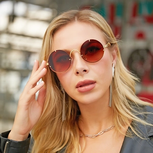 Close-up of retro round gold sunglasses with gradient brown lenses on fashion model
