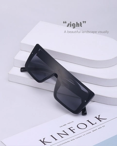 Macro shot of oversized black square sunglasses with specifications printed on inner temple