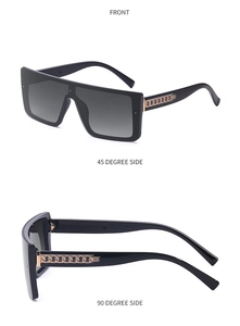 Detail of oversized black square sunglasses featuring gold chain accents on the temples