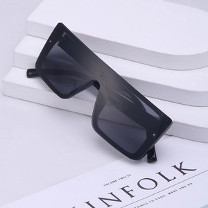 Oversized black shield sunglasses with flat top frame displayed on a modern magazine background