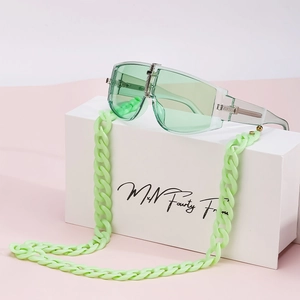 Green oversized sunglasses with matching acrylic chain on a minimalist display