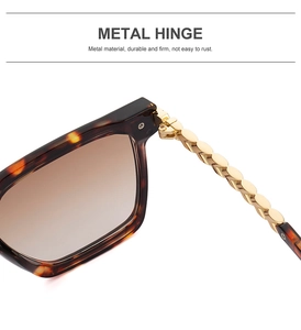 Detail of metal hinge and gold chain design on tortoiseshell sunglasses frame