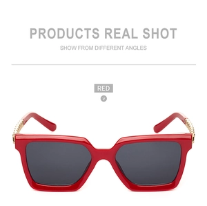 Detail of red square sunglasses with golden chain metal decoration on the temple
