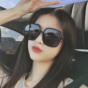 Classic black oversized square sunglasses worn by a female model inside a car setting