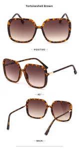 Detail view of large tortoise shell sunglasses with gradient brown lenses and metal hinges