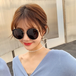Fashionable black round sunglasses with gold metal temples shown on a female model