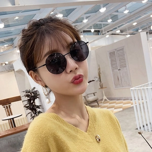 Close-up of a stylish woman wearing black oversized square sunglasses in bright setting