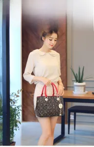 Detail of printed crossbody bag with red handles and gold pendant on model