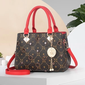 Close-up of printed handbag with gold accents, red handles, and star pendant detail