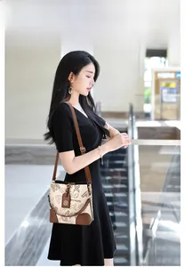 Détail d'un sac seau beige vintage avec finitions en cuir marron et bandoulière réglable