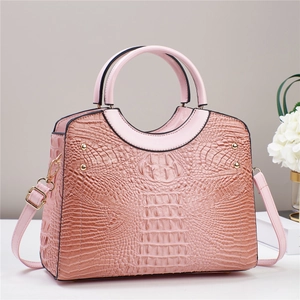Detail of pink crocodile embossed tote bag with gold rivets and smooth circular handles