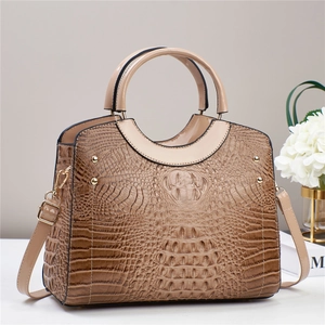 Close-up of brown crocodile pattern handbag with glossy finish and golden metal rivets