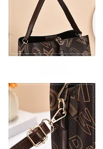 Gros plan sur la boucle dorée et les coutures d'un sac seau marron vintage monogrammé