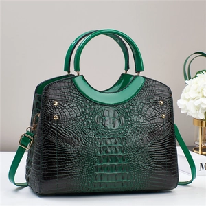 Detail view of green crocodile pattern tote bag with gold studs and adjustable strap