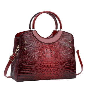 Burgundy crocodile pattern handbag with dual round handles and gold hardware accents