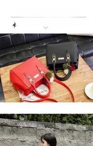 Detail of red and black leather handbags with gold clasps and pompom keychain charms