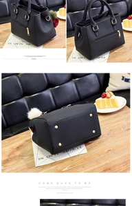 Detailed view of black litchi texture handbag featuring gold zipper and fur ball charm