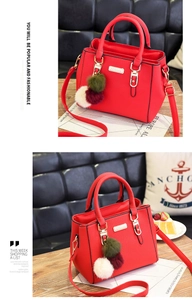 Detail view of red pebbled leather handbag with gold hardware and three-color fur pompom
