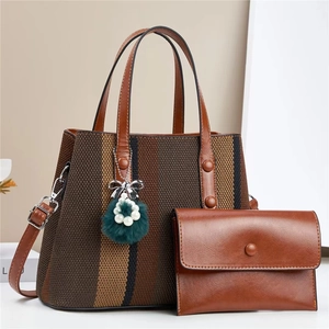 Detail of striped woven tote bag with brown faux leather pouch and plush charm