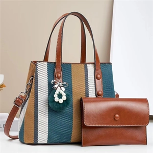 Detailed view of striped canvas tote bag with pearl pompom charm and leather wallet
