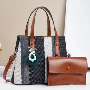 Detail view of striped canvas tote with brown leather handles and matching clutch bag