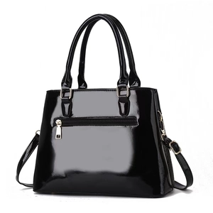 Detail of glossy black patent leather handbag with back zipper pocket and gold-tone hardware