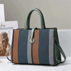Close-up of tricolor woven texture with green leather trim and golden metal clasp