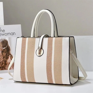 Detail of structured bicolor crossbody bag with metal twist lock and canvas texture
