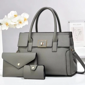 Three-piece grey pebbled leather tote set with shoulder bag and clutch in elegant setting