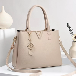 Detail of beige lychee pattern tote with gold V-hardware and adjustable strap