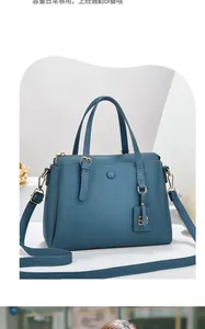 Detail view of a dark blue lychee pattern leather handbag with adjustable shoulder strap