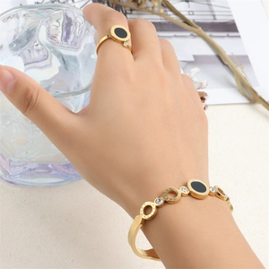 Detail of gold Roman numeral jewelry set with black inlay and crystals on hand
